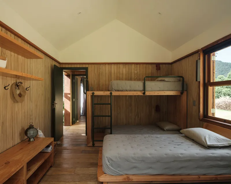 Bedroom with timber-clad walls, gabled plywood ceiling, and bunk bed with metal ladder