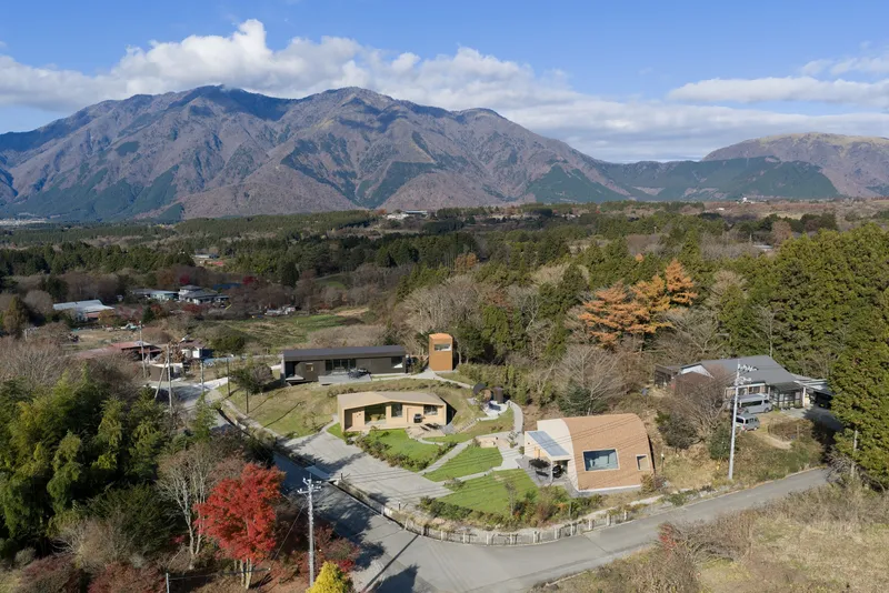 Aerial view of the curved roof compound with distant mountains and autumn foliage in foreground