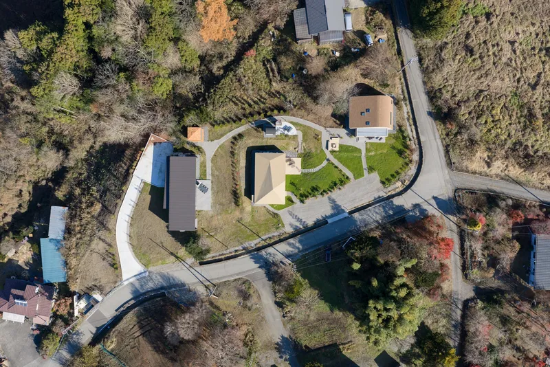 Aerial view of curved residential compound with planted beds and winding pathways among bare trees