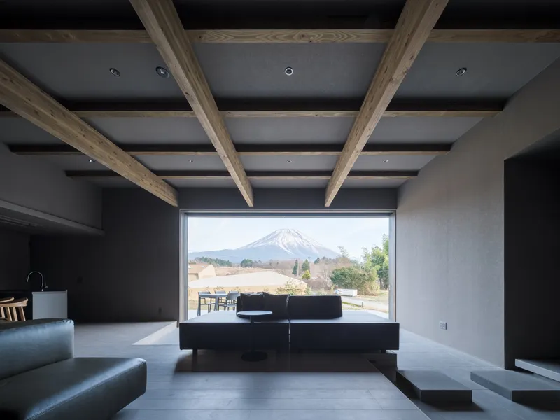 Living room with exposed timber beams and horizontal window overlooking mountain landscape