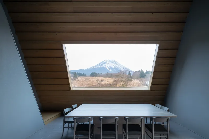 Dining table beneath a rectangular skylight framing view of snowy mountain