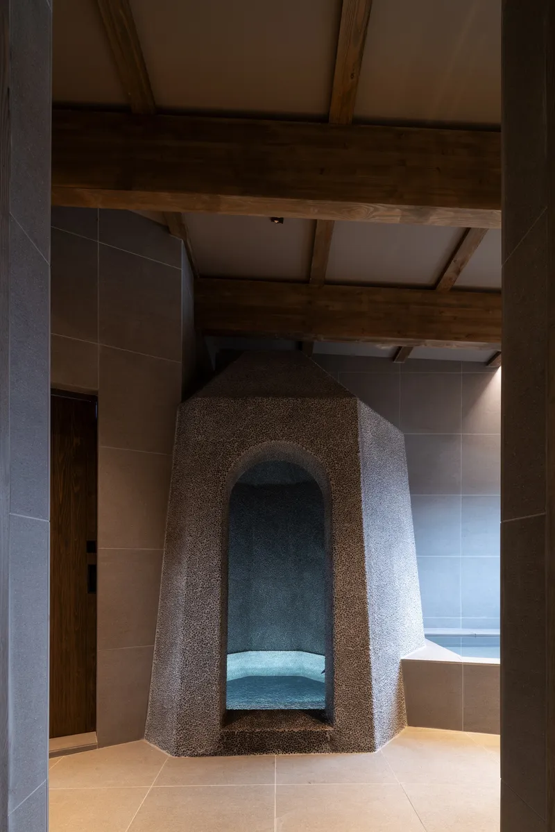 View through timber columns framing the freestanding stone alcove with arched niche seating