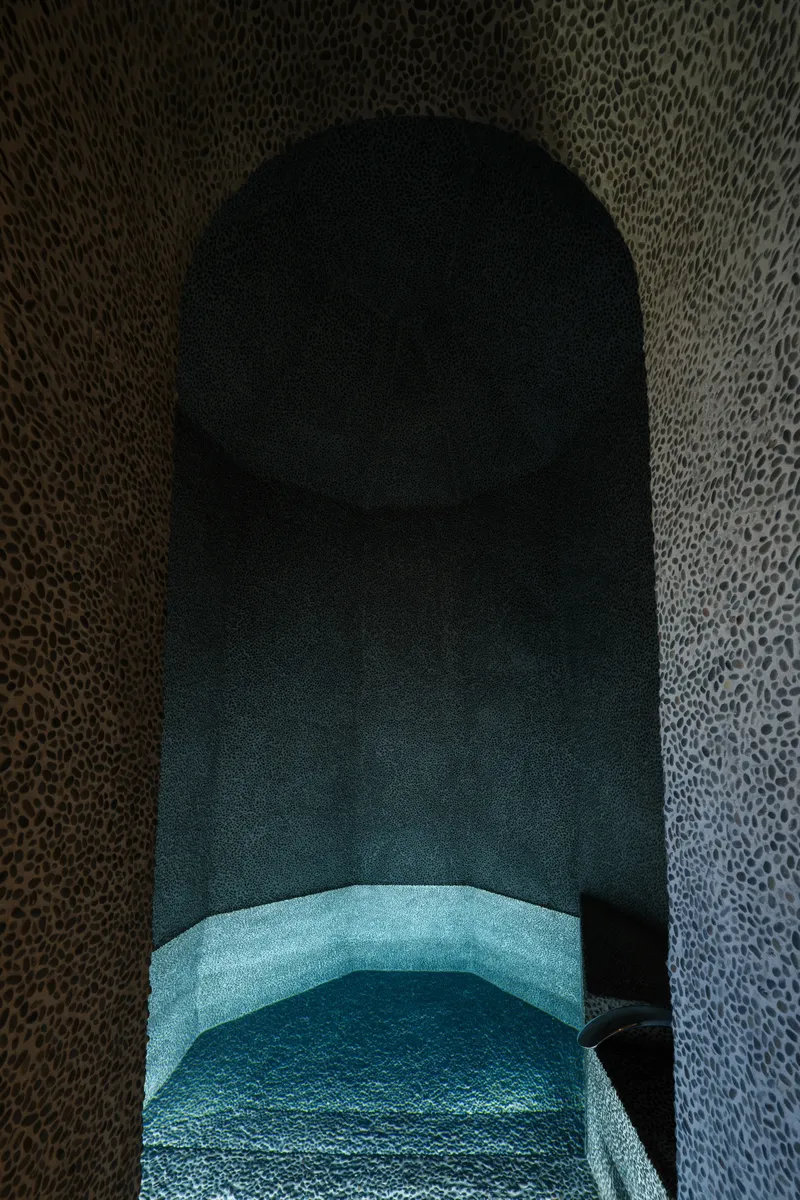Close-up inside the vaulted stone niche showing the curved turquoise bench seat