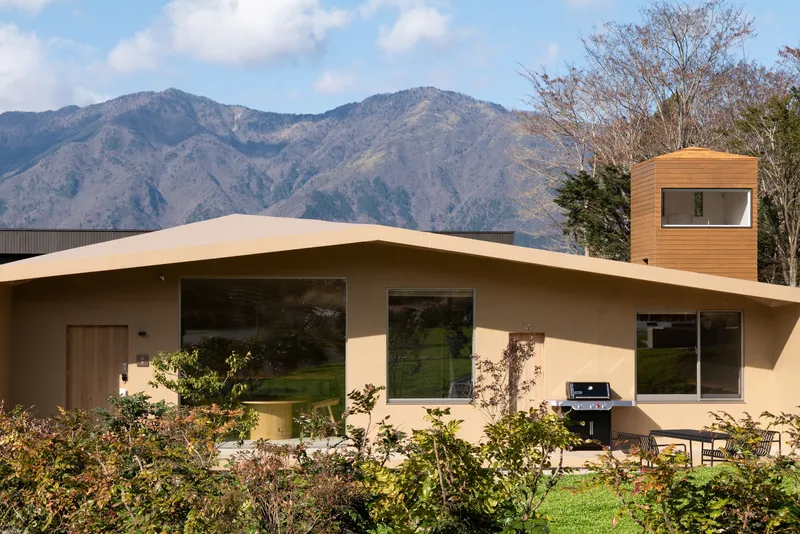 Curving plaster roof and timber-clad tower against mountain ridges in late autumn