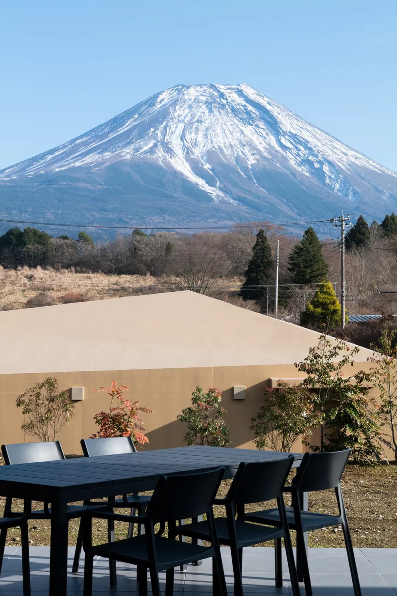 Outdoor dining terrace with snowcapped volcanic peak visible beyond the stucco privacy wall