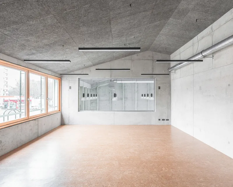 Corner room with linoleum flooring and a glazed interior partition overlooking an adjacent space