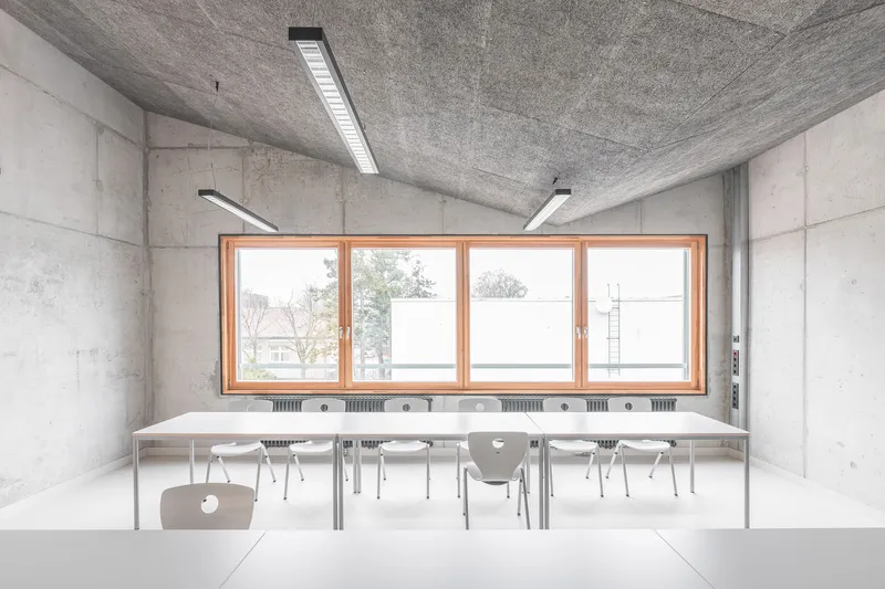 Classroom with paired tables and chairs facing a continuous window with radiators below the sill