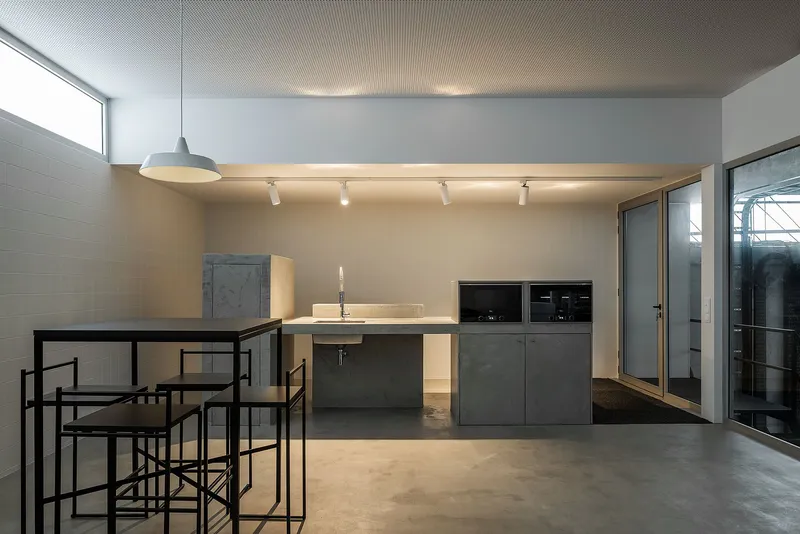 Minimal industrial canteen with clean lines and integrated kitchen core
