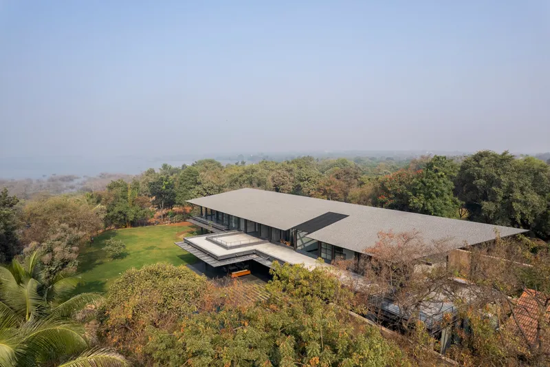 Aerial view of the twin flat roofs over a wooded hillside in misty morning light
