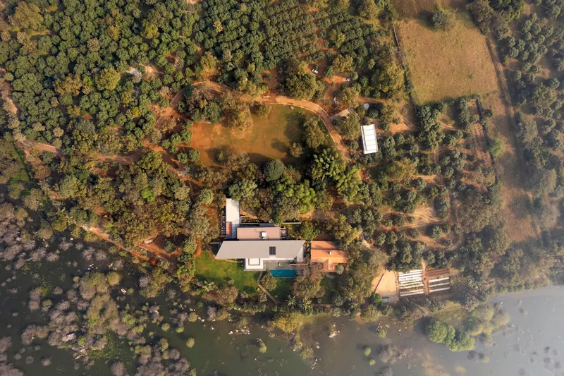 Aerial view of the residence nestled within dense tree canopy and cleared lawns with pool and pathways visible