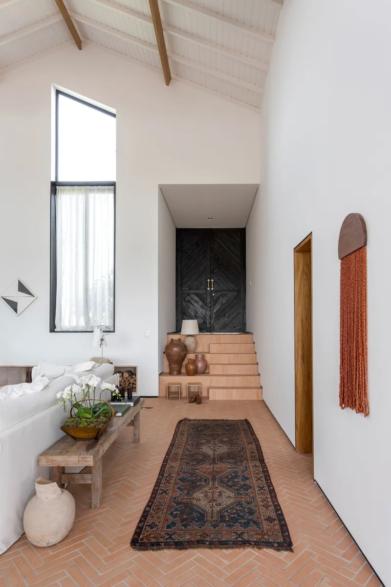 Entry hall with herringbone terracotta floor and exposed timber rafters beneath a vaulted ceiling
