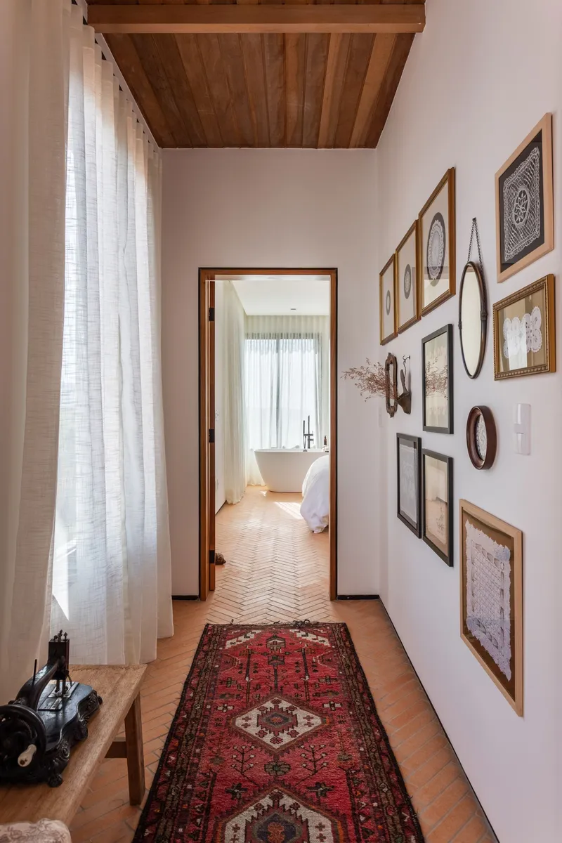 Narrow hallway with gallery wall of framed artworks and timber ceiling inset above herringbone floor