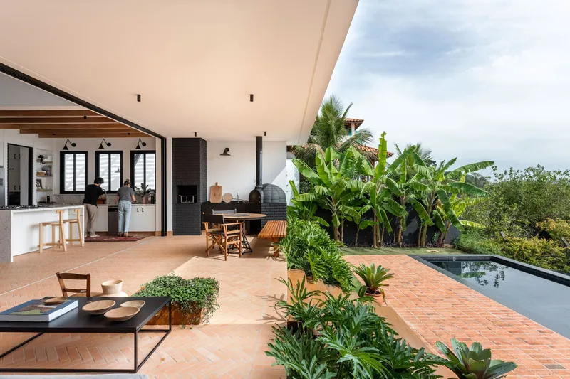Covered terrace overlooking terracotta-paved deck with planted beds and pool edge