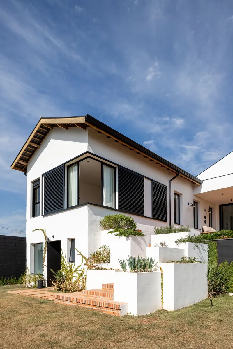 White stucco facade with horizontal black shutters and tiered planter boxes under a blue sky