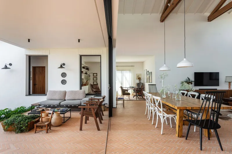 Open-plan living and dining space with herringbone terracotta flooring and exposed timber roof beams