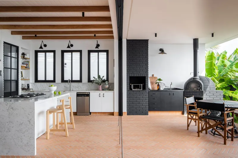 Kitchen with white marble island, black brick fireplace and exposed timber ceiling beams