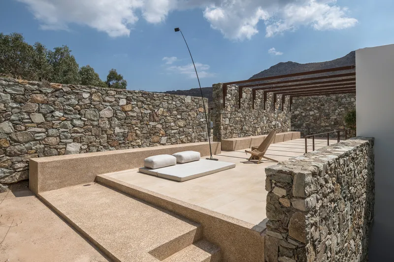 Stone terrace with stepped platform and low seating surrounded by stacked stone walls under clear sky