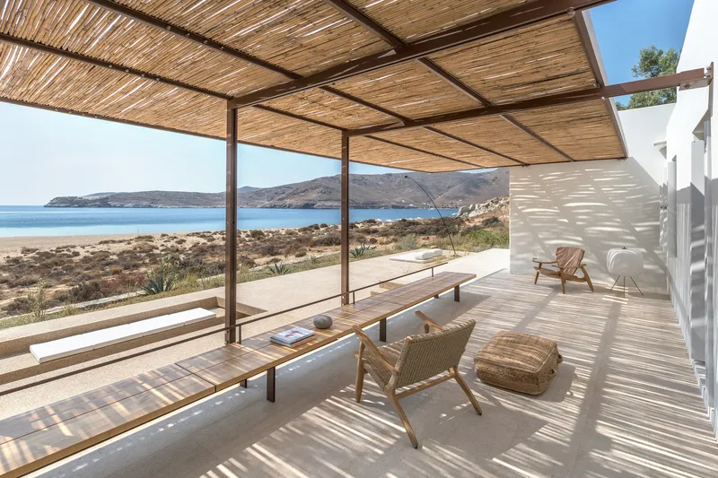 Covered terrace with reed canopy and steel frame overlooking coastal scrubland and distant bay