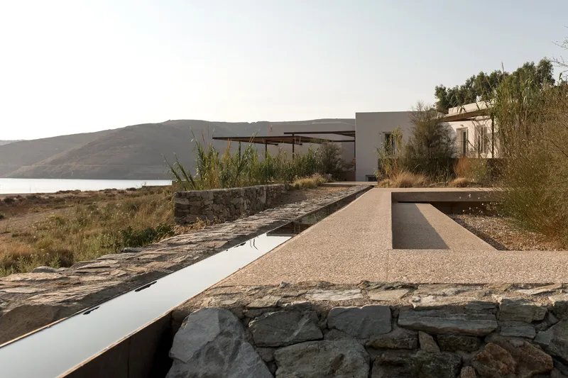 Stone retaining wall and gravel terrace stepping down toward the hillside and water
