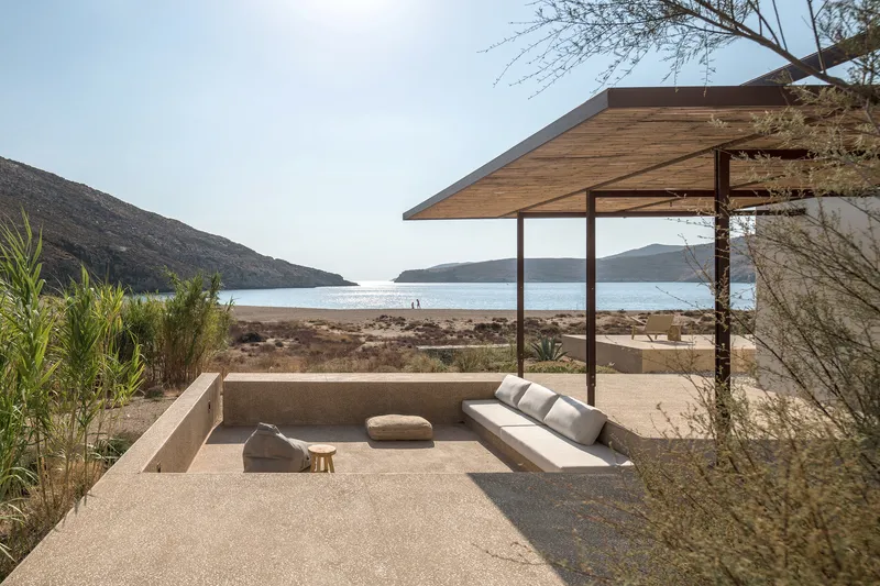 Sunken seating area with timber canopy and built-in bench facing the bay at dusk