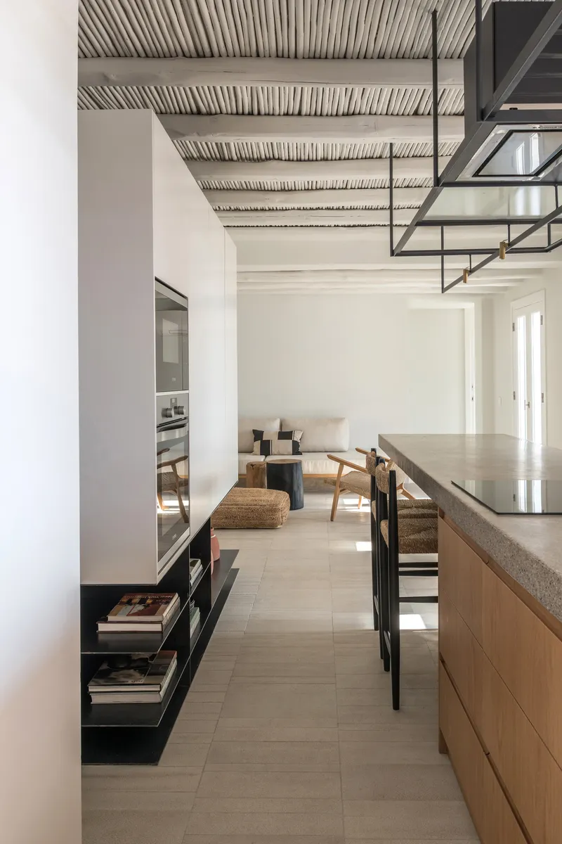 Kitchen with terrazzo island, exposed ceiling structure, and steel mezzanine staircase overhead