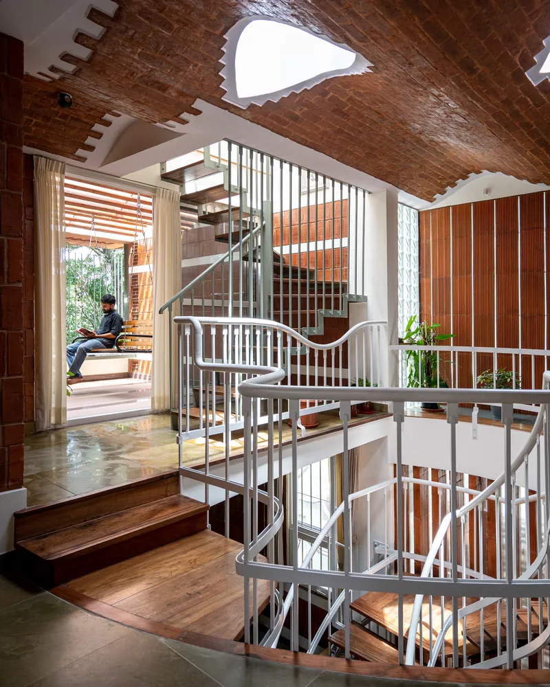 Multi-level spiral staircase with person sitting at threshold opening to exterior terrace