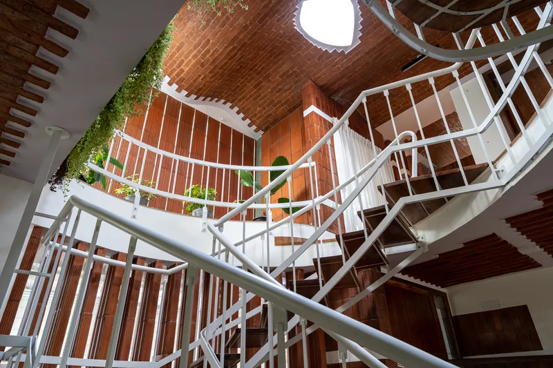 Looking up at the spiral staircase wrapped with vertical planters along the vaulted brick barrel ceiling