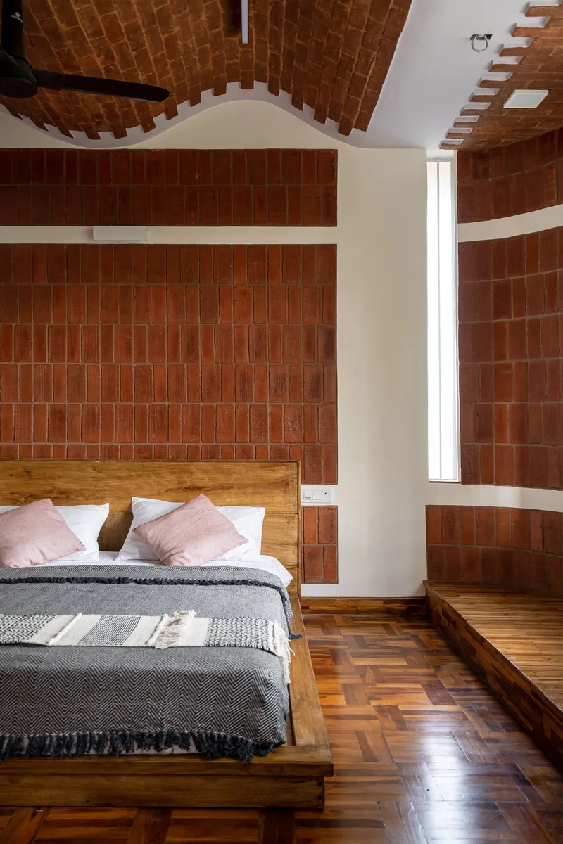 Red clay tile accent wall with white trim bands framing a bed on parquet flooring