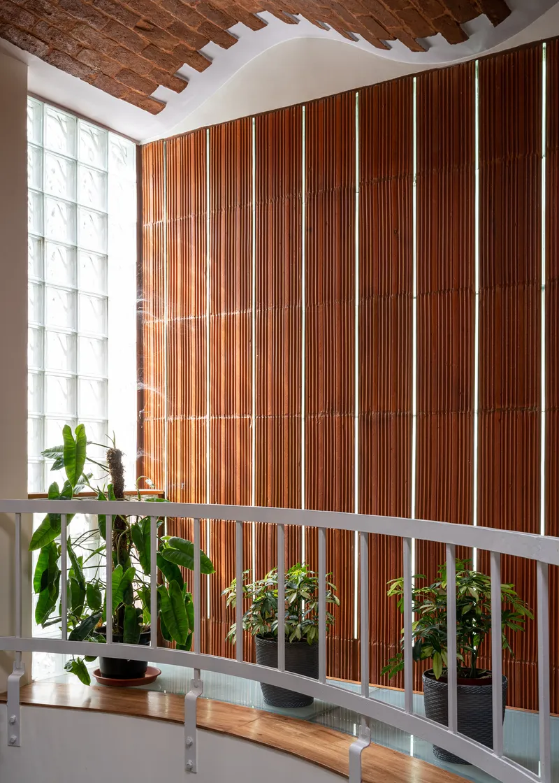 Vertical wood slat wall behind a white railing with potted plants and glass block window