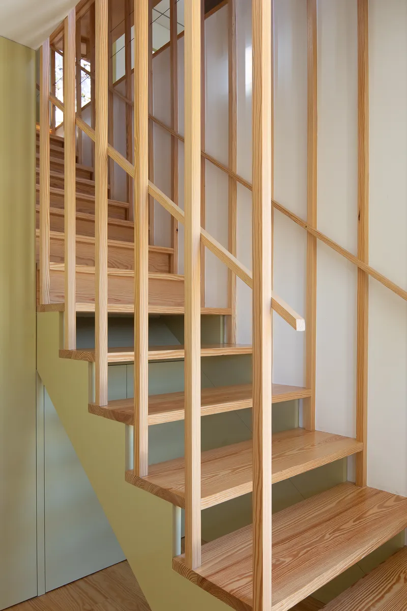 Timber staircase with vertical slat railings and pale green wall panel under the treads