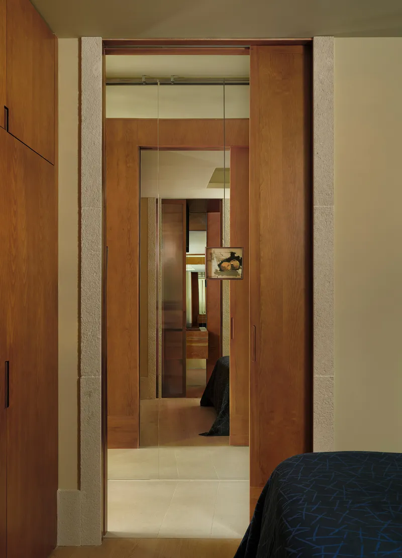 View through sliding timber doors into a hallway with limestone portal frames