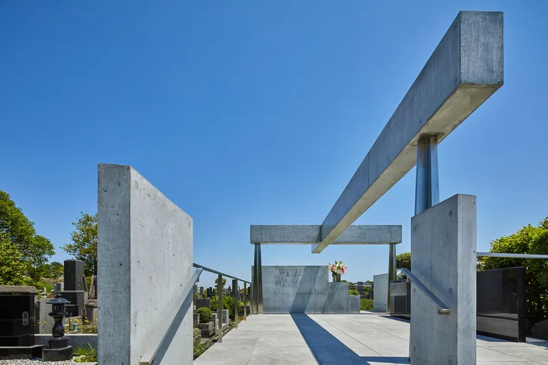Concrete portal frame structure with columns and beams over a paved plaza under clear blue sky