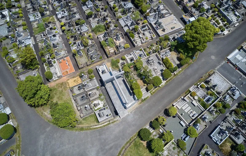 Drone perspective showing the memorial's linear axis aligned with surrounding burial plots and asphalt pathways between green plantings