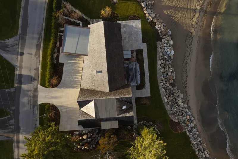 Aerial view of the interlocking volumes with courtyard and planted beds along the rocky shoreline