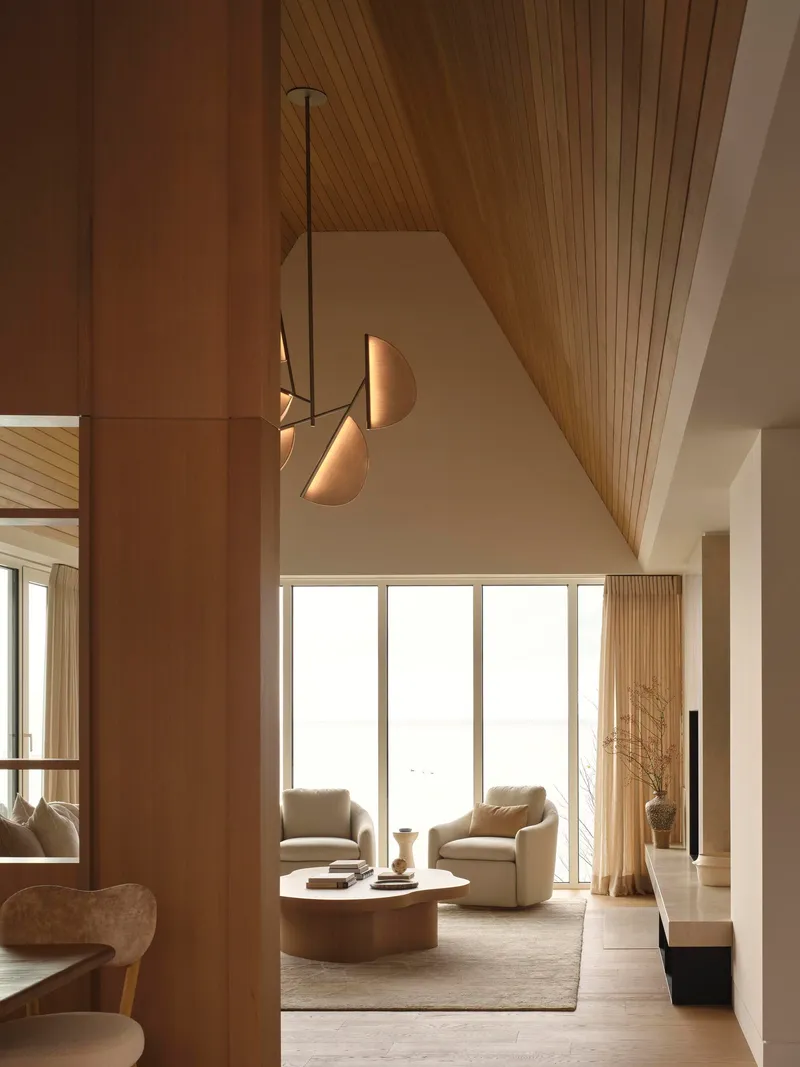 Living room with vaulted timber ceiling and pendant lighting above seating area facing tall windows