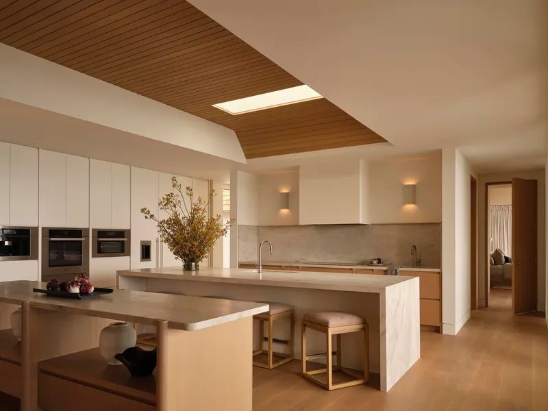 Kitchen with timber ceiling panels, central island, and integrated dining table under skylight