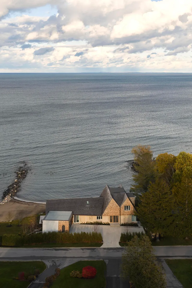 Elevated view of the compound with gabled roofs nestled between shoreline and residential street