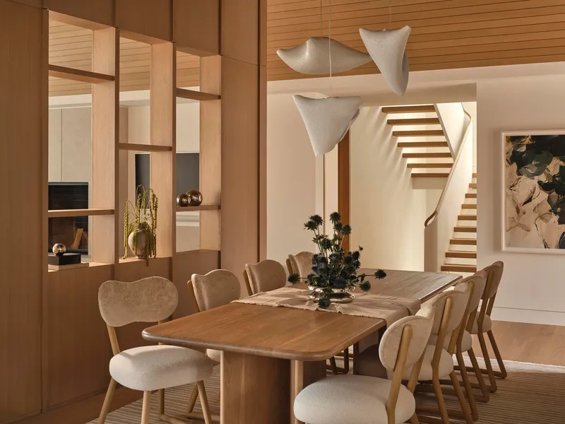 Dining area with open shelving partition and timber staircase visible in the evening light