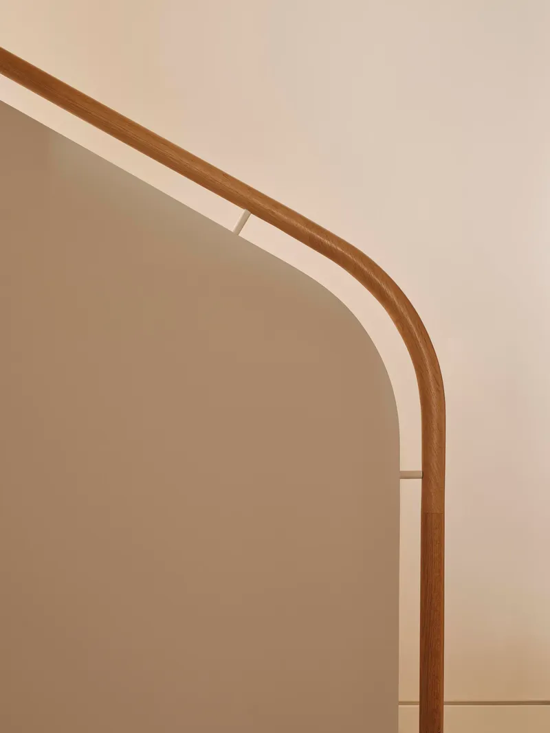 Close-up of the rounded timber handrail curving along a plastered archway edge