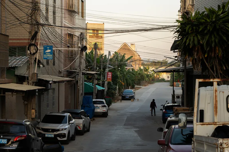 Residential street framed by overhead power lines and parked vehicles at dusk