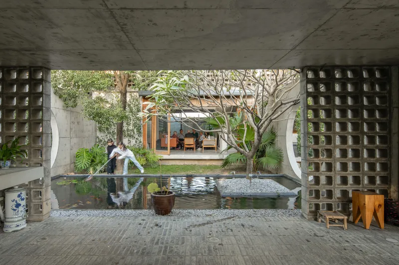 Covered terrace with reflecting pool and perforated concrete block screens overlooking a planted courtyard