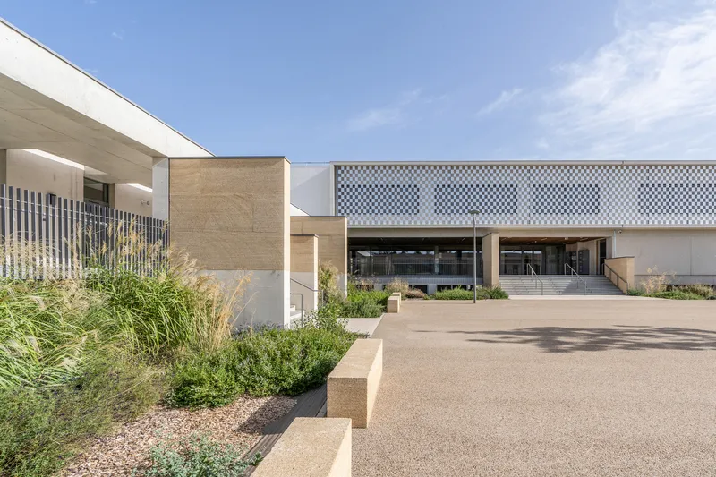 Entry drive framed by gravel beds with grasses and chequered facade screen panel