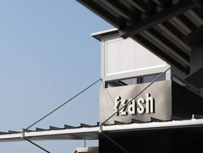 Exterior signage and white metal canopy detail with corrugated roofing in afternoon light