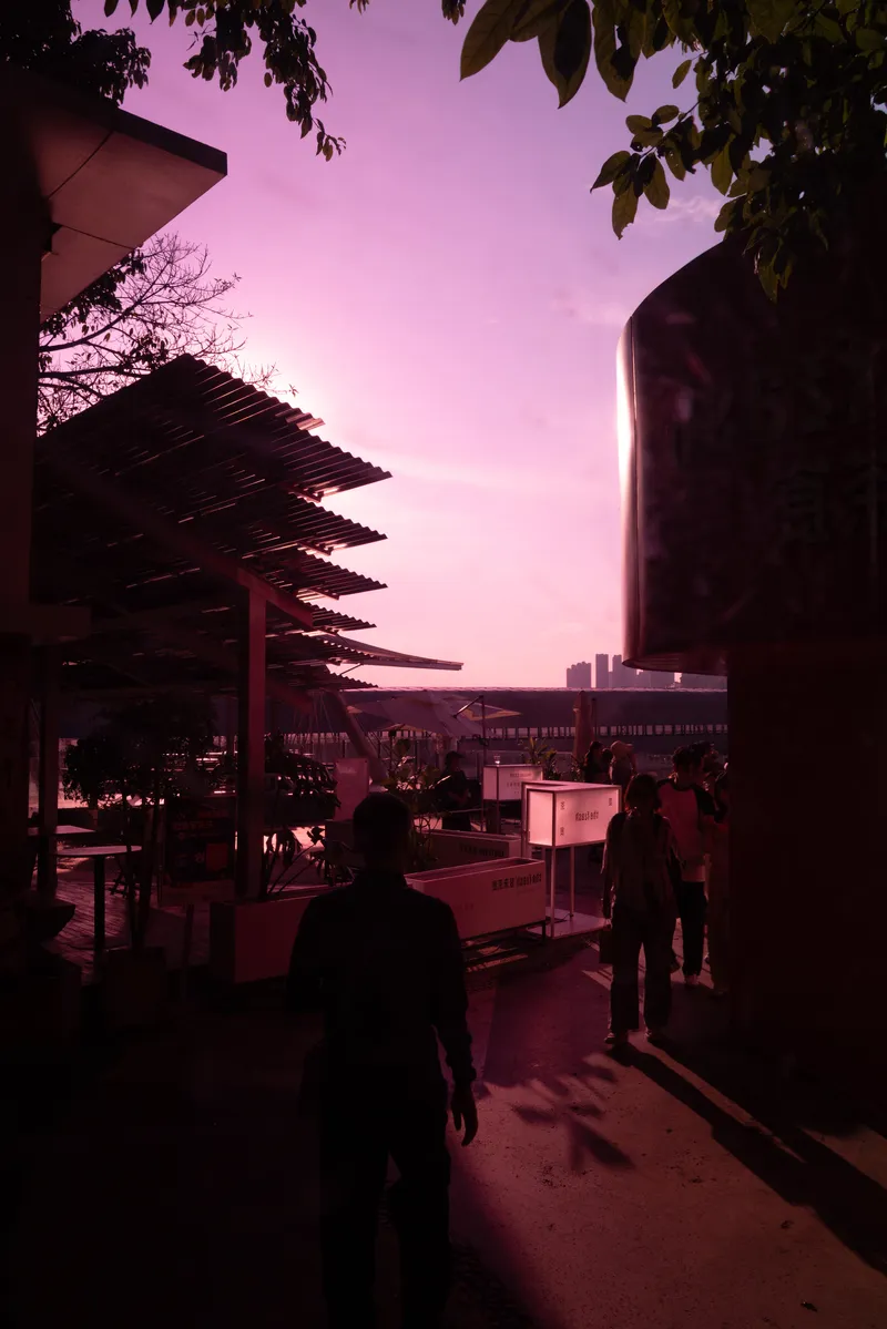 Outdoor terrace with slatted canopy and diners under a violet twilight sky