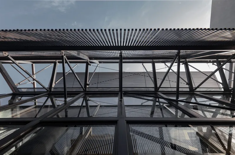 Looking up at the exposed steel cross-bracing and corrugated metal ceiling louvers