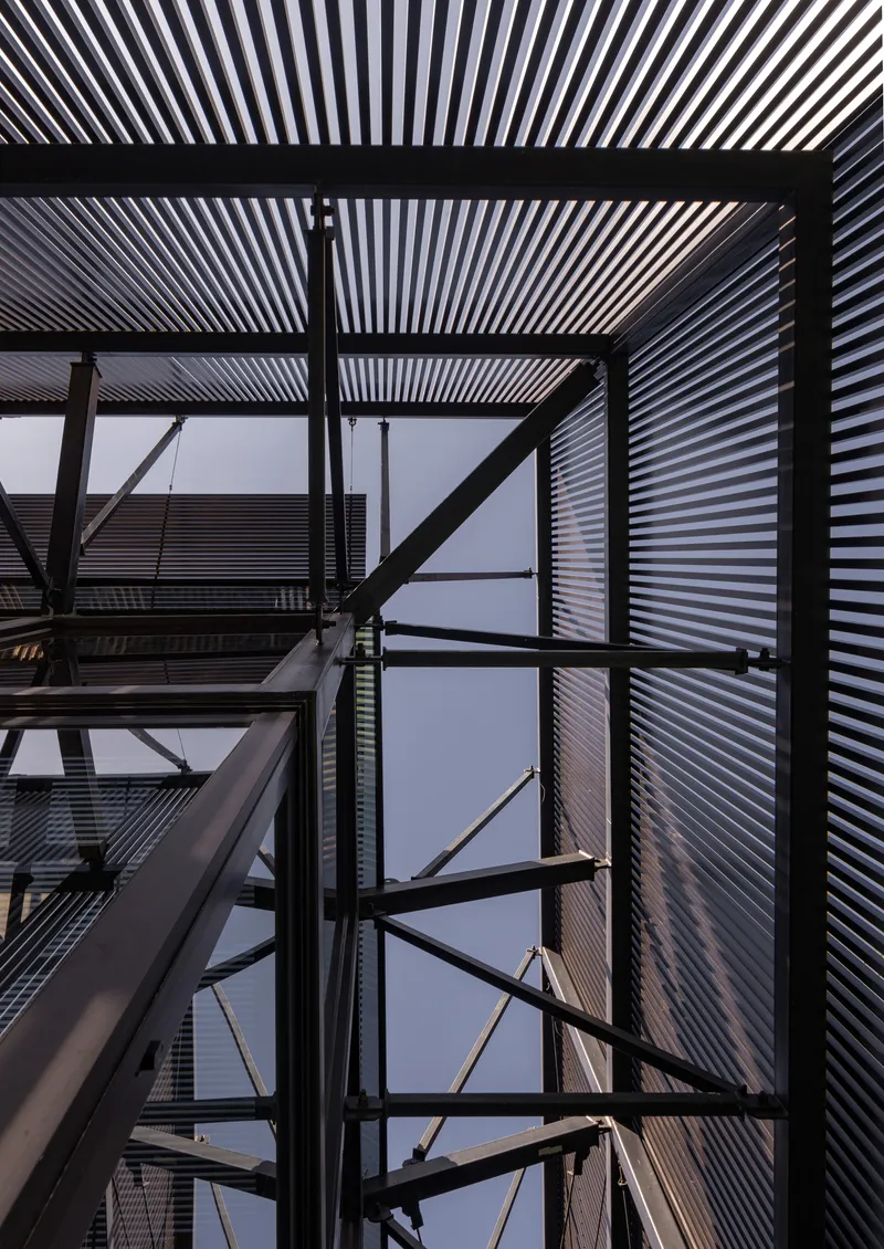 Looking up through the exposed steel frame structure with corrugated metal cladding against dusk sky
