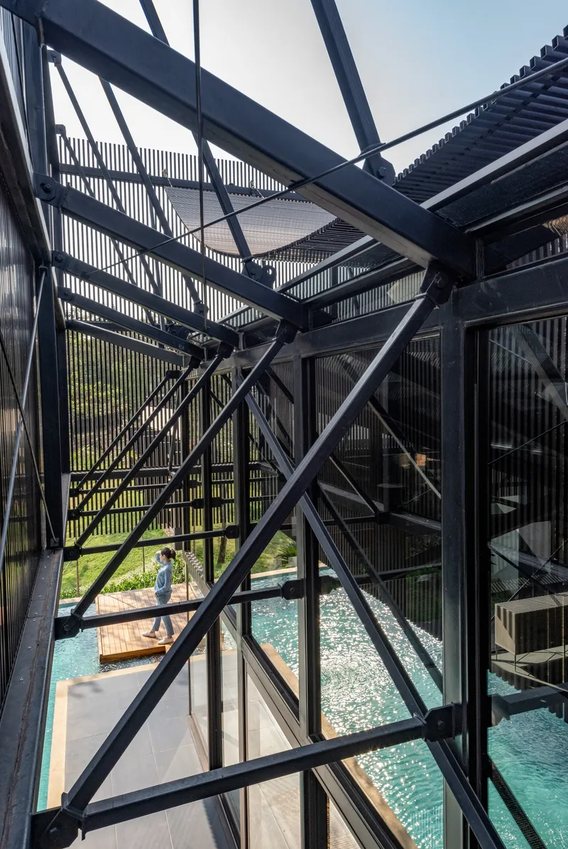Interior view through the steel structure showing the courtyard pool and figure walking on deck