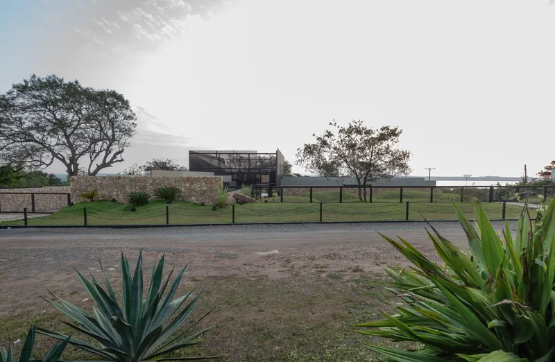 Distant view of the elevated steel and screen volume above a stone retaining wall at dusk