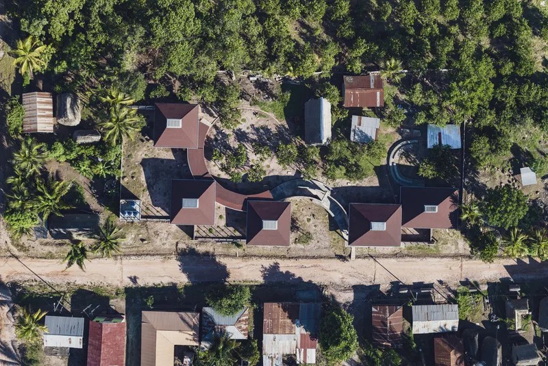 Aerial view of red tile roofs clustered among palm trees and dense tropical vegetation