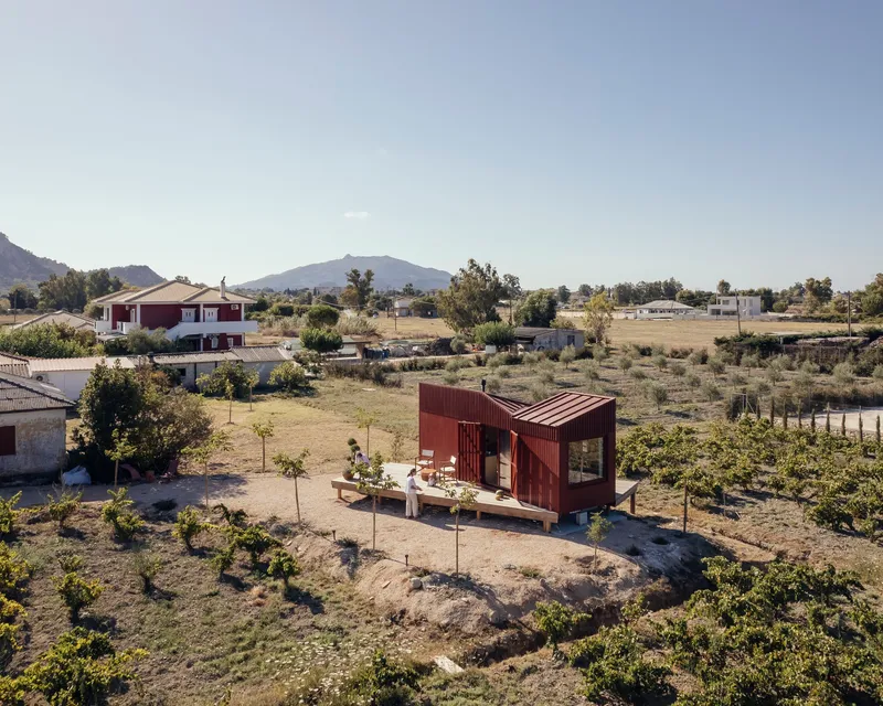 Aerial view of the corrugated metal structure elevated on a deck among young trees and vines